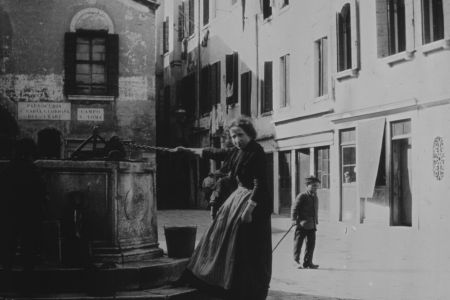 Frau holt Wasser aus einem Brunnen.