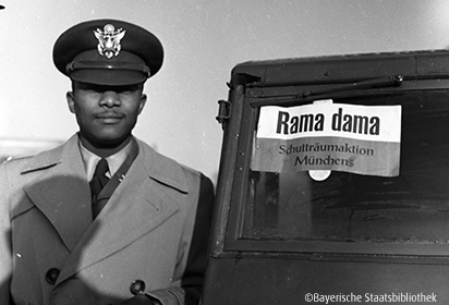Foto eines US-GIs neben einem Auto mit dem Schild Rama dama Schutträumaktion München