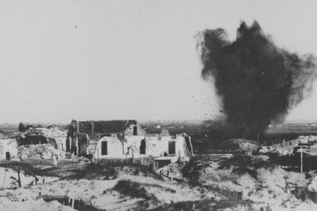 Zerstörtes Haus, rechts daneben explodiert Bombe