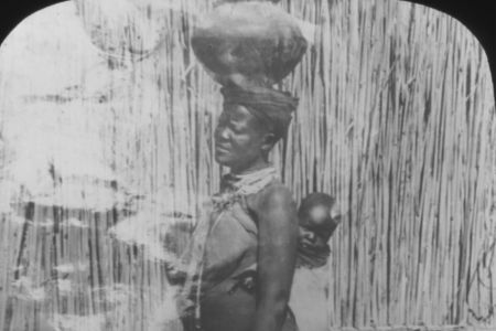 Frau mit einer Art Topf auf dem Kopf und Kind auf dem Rücken.