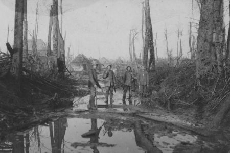 Vier Soldaten in zerstörten Waldstück vor einem Dorf