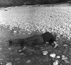 Schwarz-weiß-Foto, dass einen leblosen, menschlichen Körper zeigt. Die Szene ist gestellt